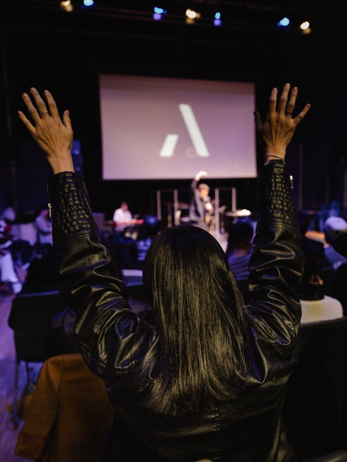 An enthusiastic worship gathering with people raising hands during a church service
